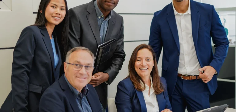 Diverse team of business advisors smiling and gathered around a meeting table