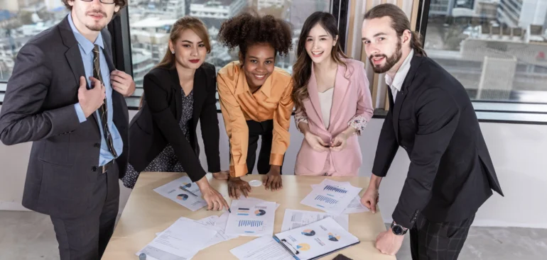 Team of diverse professionals collaborating on business strategies and analyzing reports together at a modern office table.