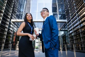 Confident business partners networking outside a corporate office building while discussing growth opportunities.