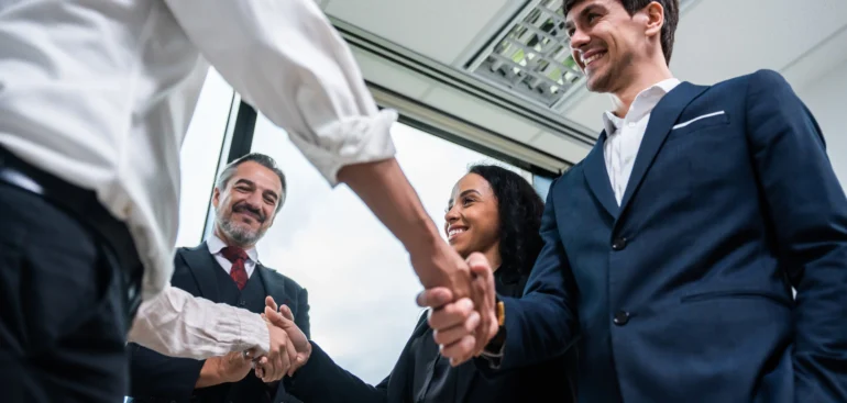Business partners shaking hands after reaching a franchise agreement in a modern office.
